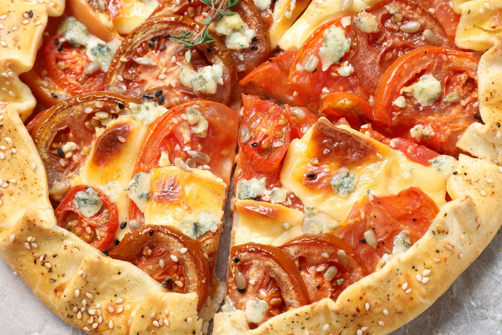 Photo of Tasty galette with tomato and cheese (Caprese galette) on parchment, top view