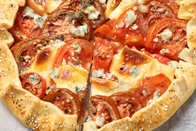 Tasty galette with tomato and cheese (Caprese galette) on parchment, top view