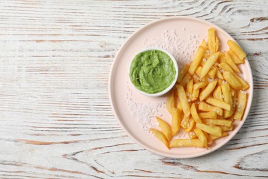 Plate with french fries and avocado dip on white wooden table, top view. Space for text