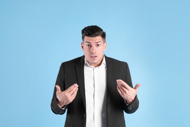 Photo of Emotional man in suit pointing at himself on light blue background
