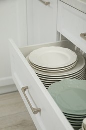 Stacks of clean plates in drawer indoors