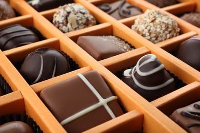 Box with different chocolate candies as background, closeup