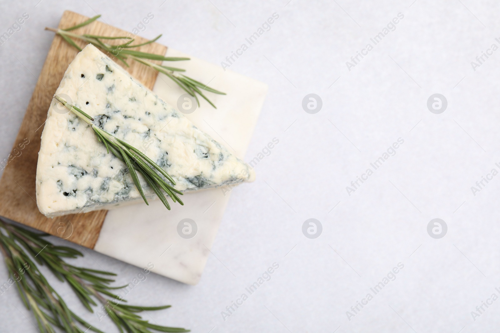 Photo of Tasty blue cheese with rosemary on light table, flat lay. Space for text