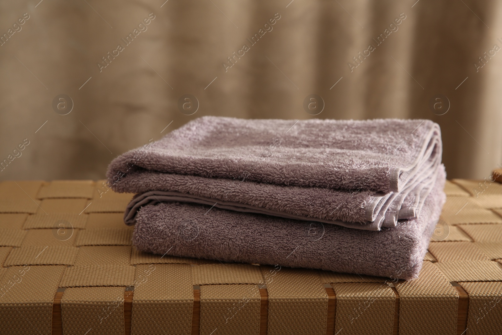 Photo of Soft terry towels on wicker bench indoors, closeup