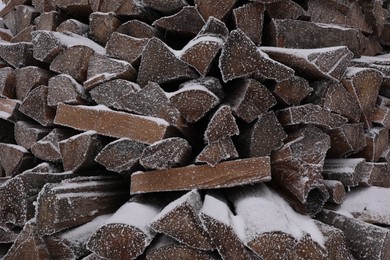 Photo of Stacked firewood with snow and hoarfrost as background, closeup