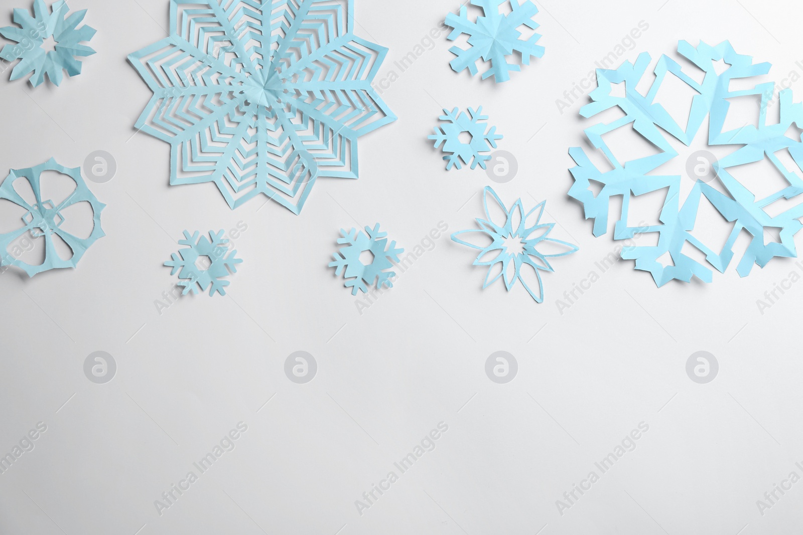 Photo of Many paper snowflakes on white background, flat lay. Space for text