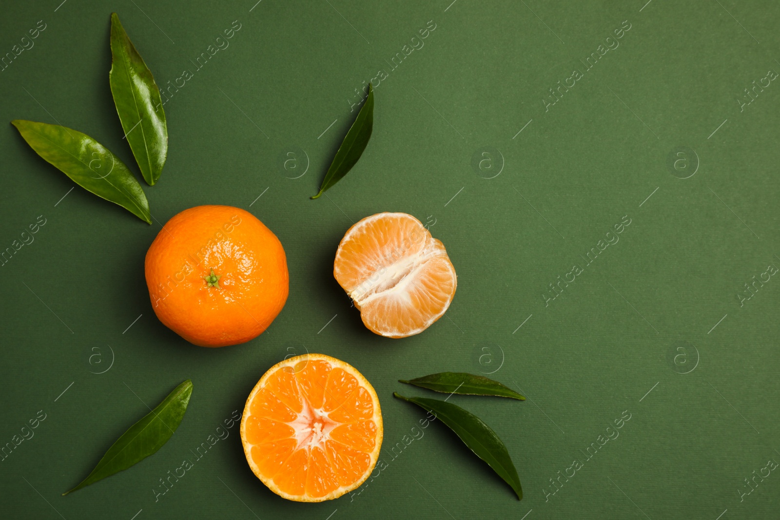 Photo of Delicious tangerines and leaves on green background, flat lay. Space for text