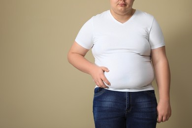 Overweight man in tight t-shirt on beige background, closeup. Space for text