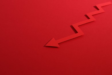 Photo of One zigzag paper arrow on red background, closeup. Space for text