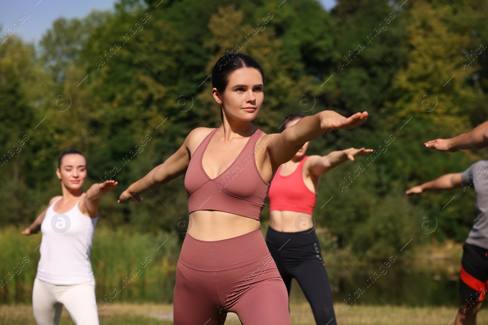 Photo of Group of people practicing yoga in park on sunny day, selective focus