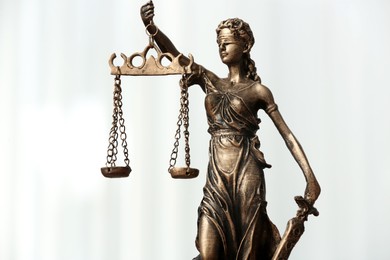 Photo of Symbol of fair treatment under law. Figure of Lady Justice on white background, closeup