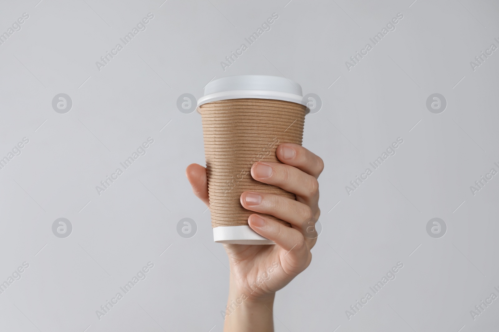 Photo of Woman holding takeaway paper coffee cup on white background, closeup