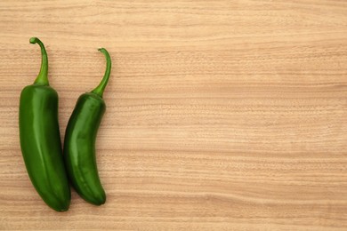 Fresh green jalapeno peppers on wooden table, flat lay. Space for text