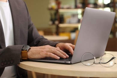 Photo of Man working on laptop at table in cafe, closeup