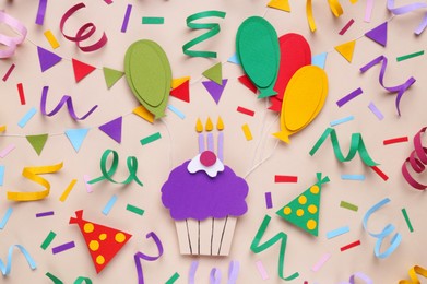 Photo of Birthday party. Paper cupcake and confetti on beige background, flat lay