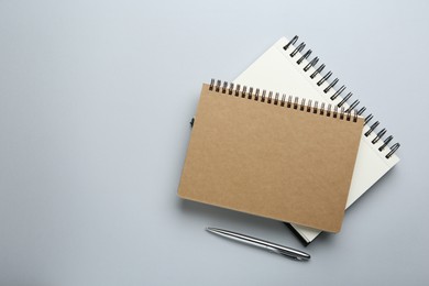 Photo of Notebooks on light grey background, top view. Space for text