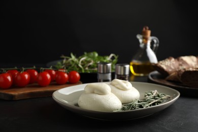 Photo of Delicious burrata cheese with rosemary on black table