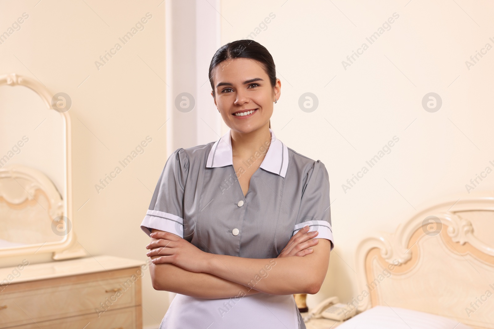 Photo of Portrait of young chambermaid near bed in hotel room