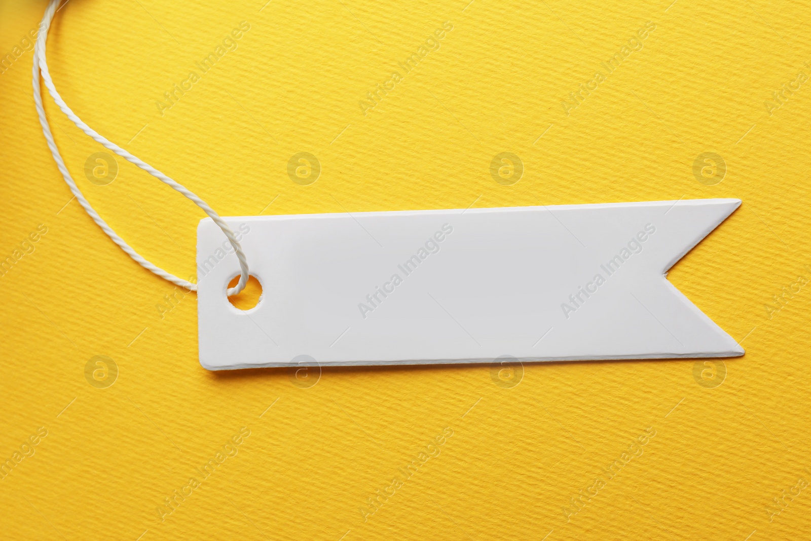 Photo of Tag with space for text on yellow background, top view