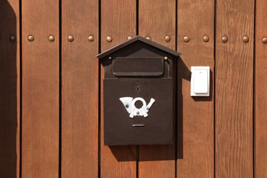 Photo of Metal letter box and white doorbell on wooden fence outdoors