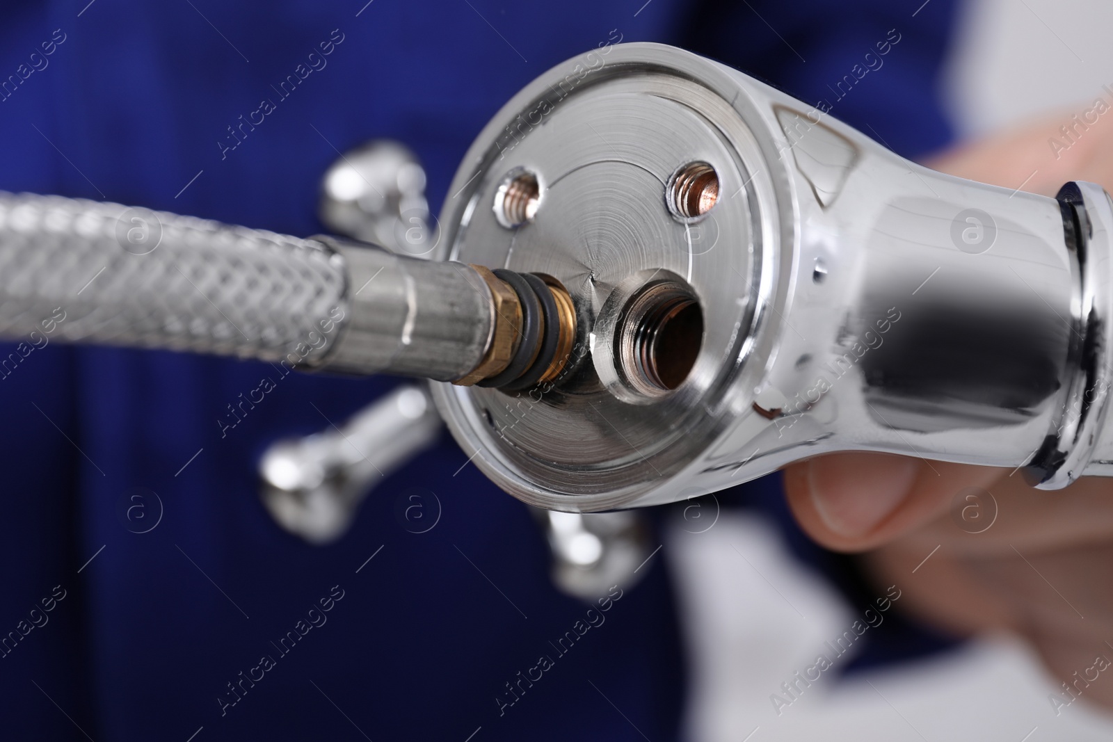 Photo of Professional plumber holding water tap on blurred background, closeup
