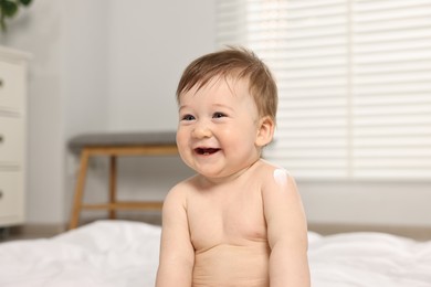 Cute little baby with moisturizing cream on body at home