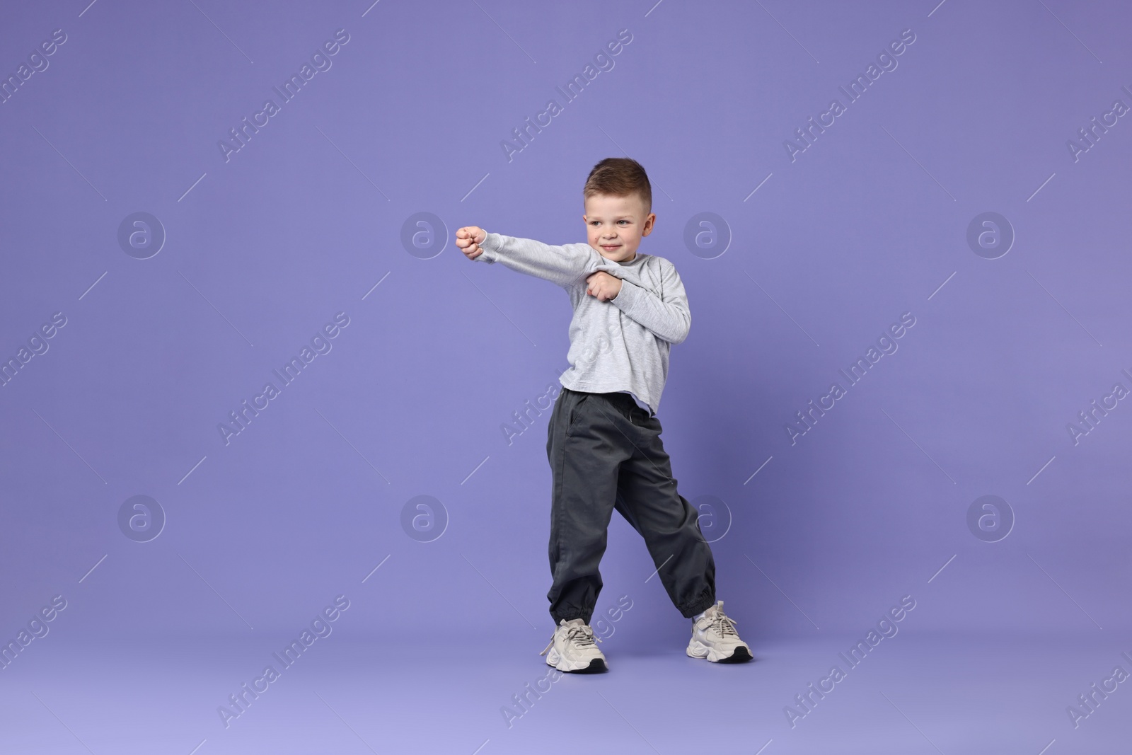 Photo of Happy little boy dancing on violet background