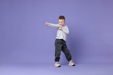 Happy little boy dancing on violet background