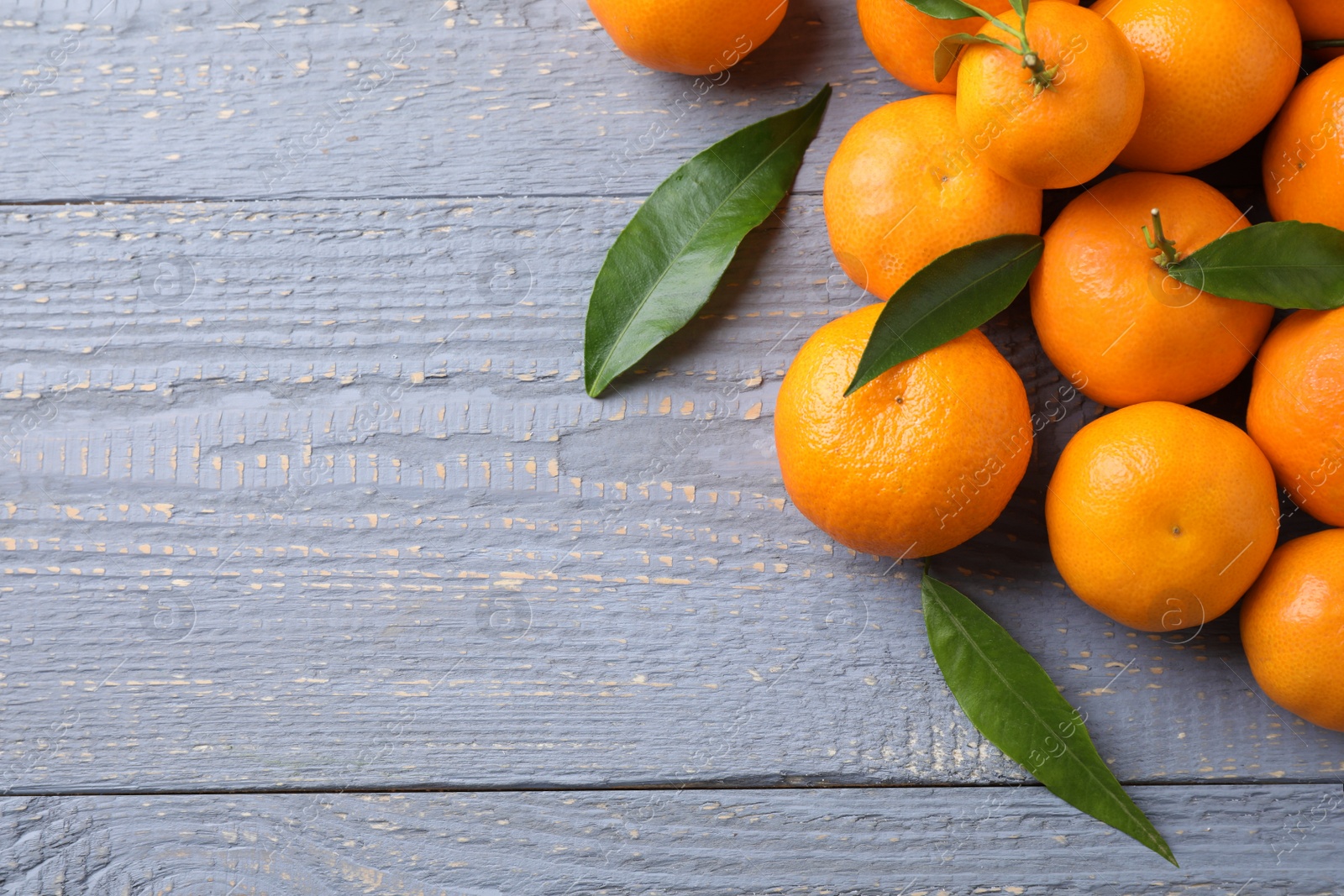 Photo of Fresh ripe tangerines on grey wooden table, flat lay. Space for text