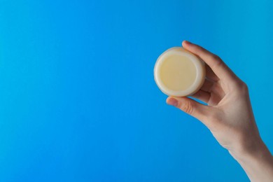 Photo of Woman holding solid shampoo bar against light blue background, closeup. Space for text