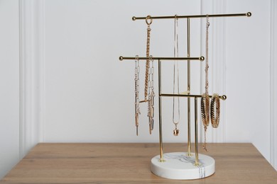 Photo of Interior element. Holder with set of luxurious jewelry on wooden table. Space for text