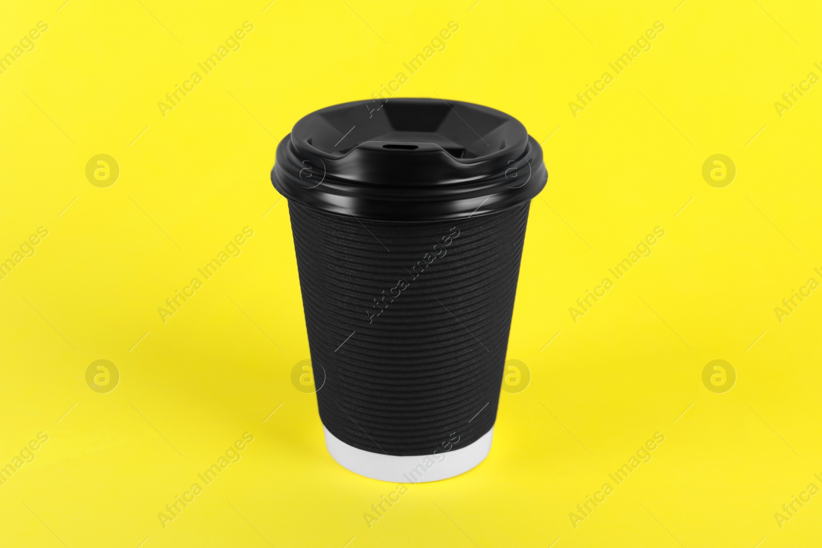 Photo of Black paper cup with plastic lid on yellow background. Coffee to go