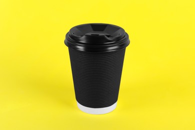 Photo of Black paper cup with plastic lid on yellow background. Coffee to go