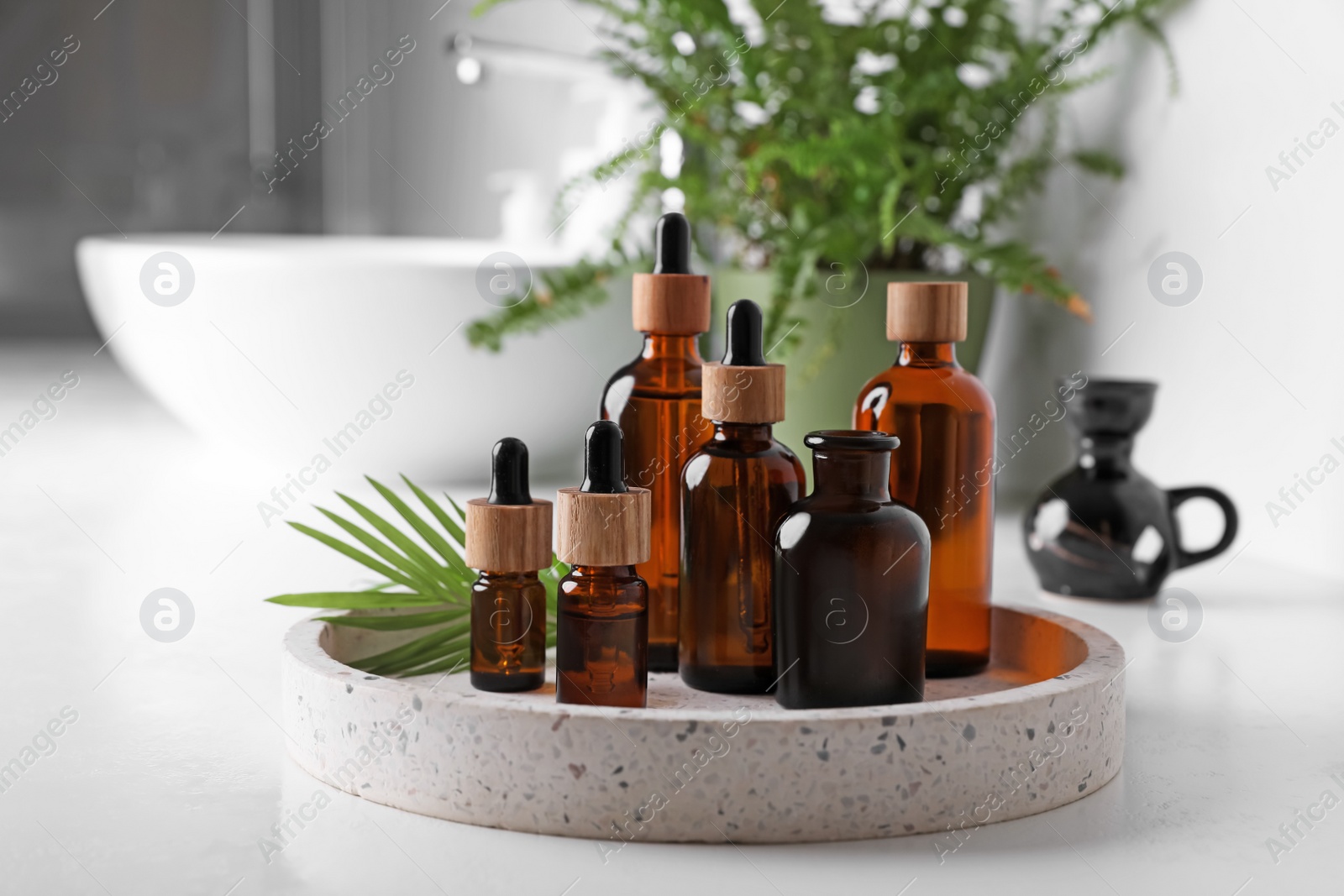 Photo of Tray with bottles of essential oils on white table in bathroom