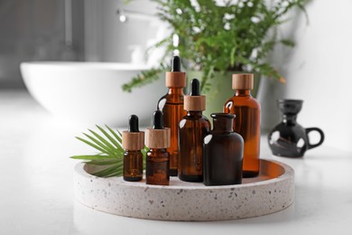 Tray with bottles of essential oils on white table in bathroom