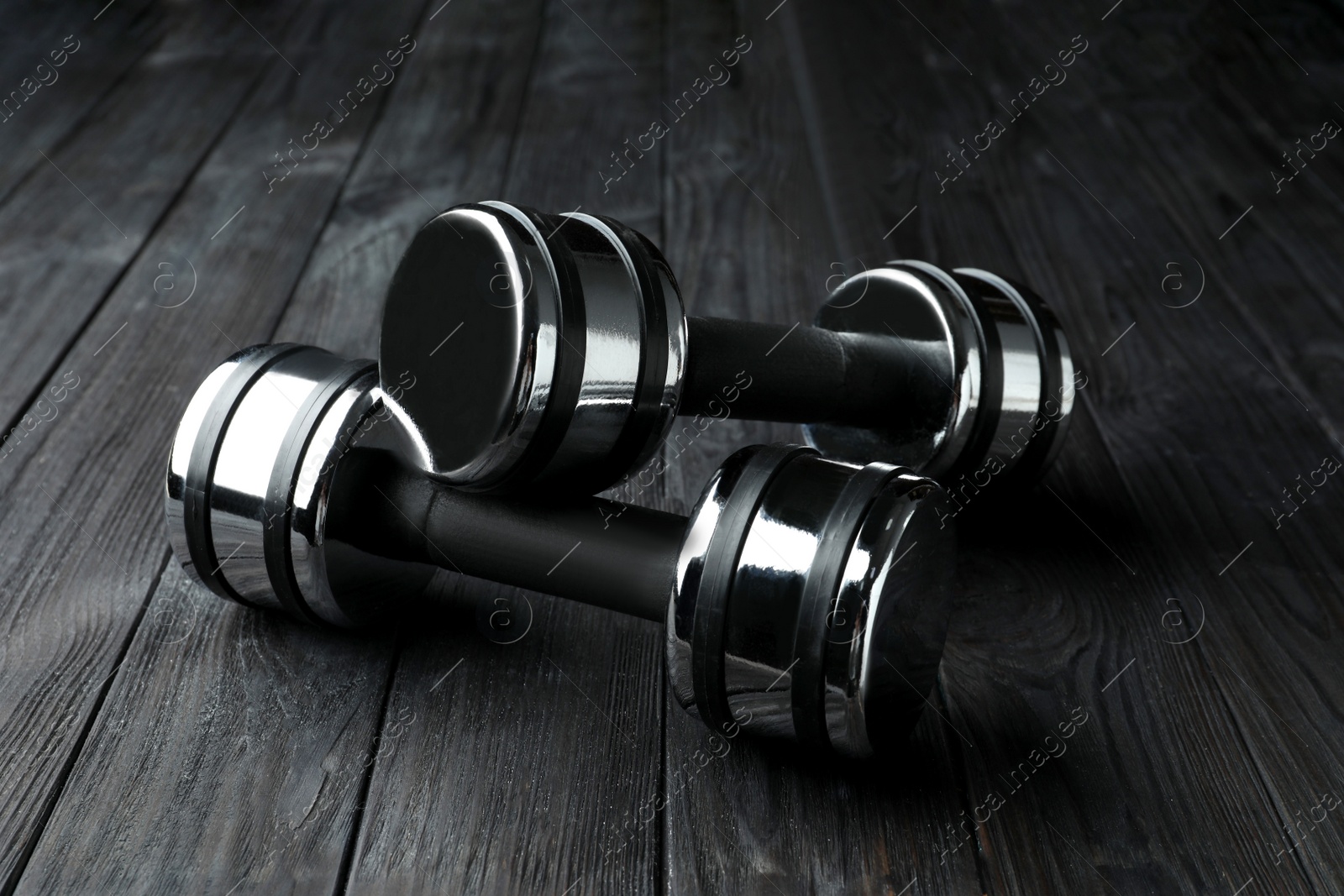 Photo of Two metal dumbbells on black wooden table