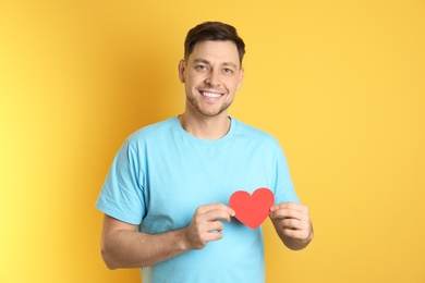 Photo of Portrait of man with paper heart on color background
