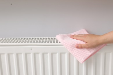 Photo of Woman cleaning radiator with rag indoors, closeup. Space for text