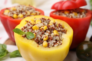 Photo of Quinoa stuffed bell peppers and basil on white table, closeup