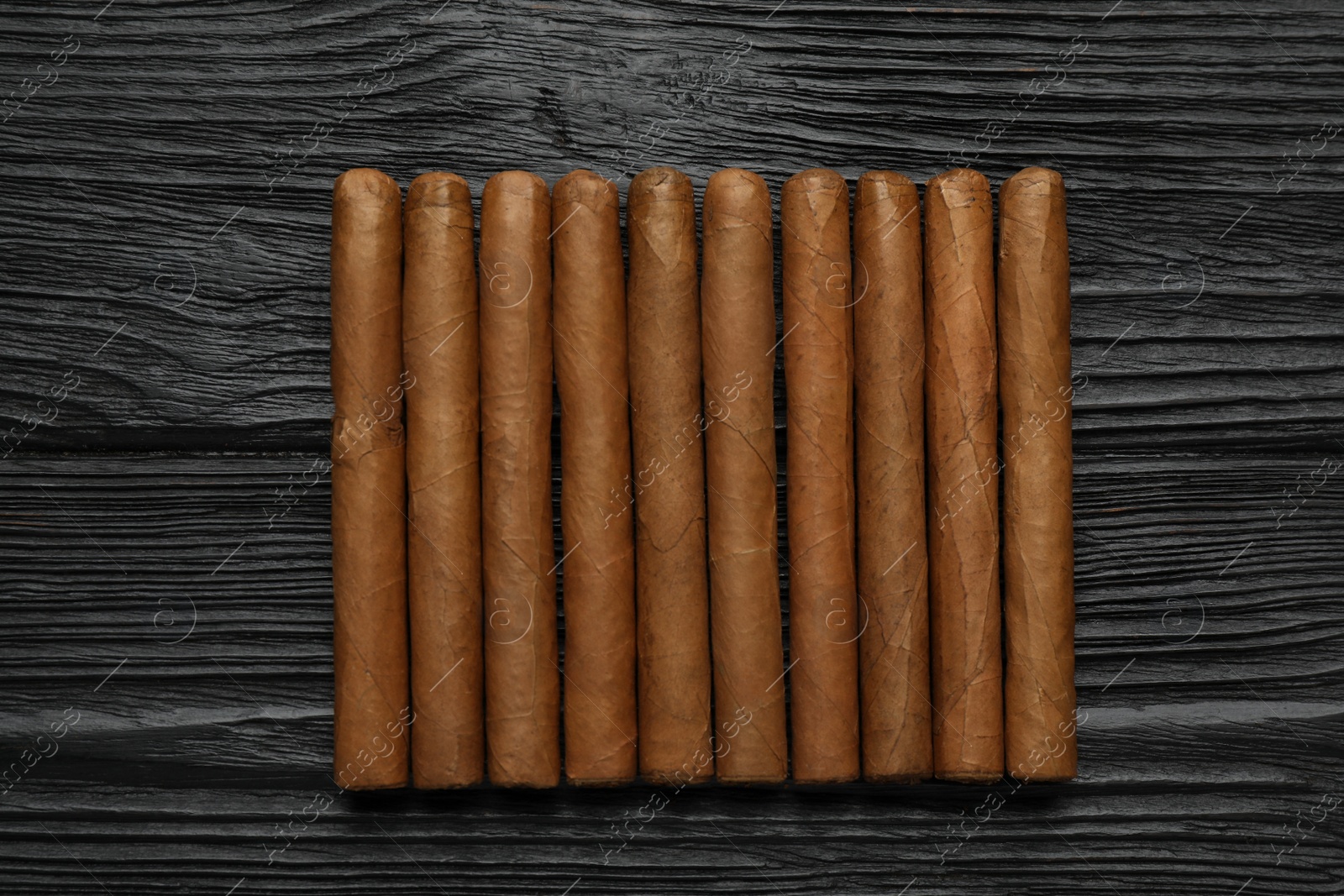 Photo of Many cigars on black wooden table, flat lay