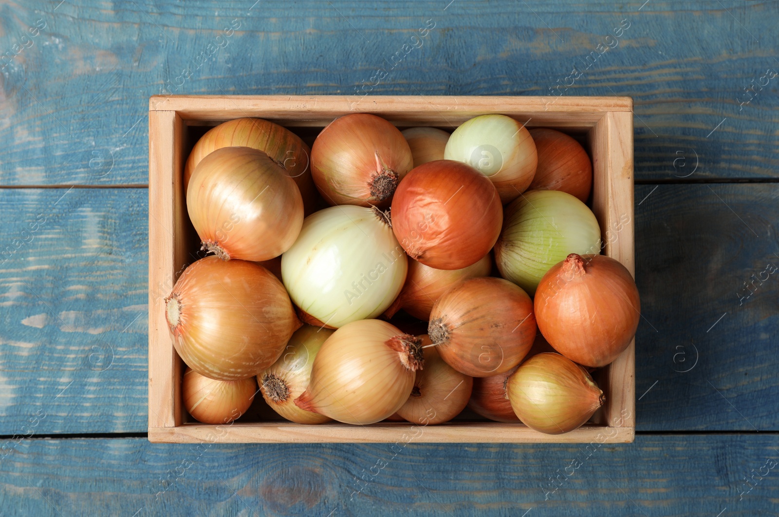 Photo of Crate full of fresh onion bulbs on wooden background, top view