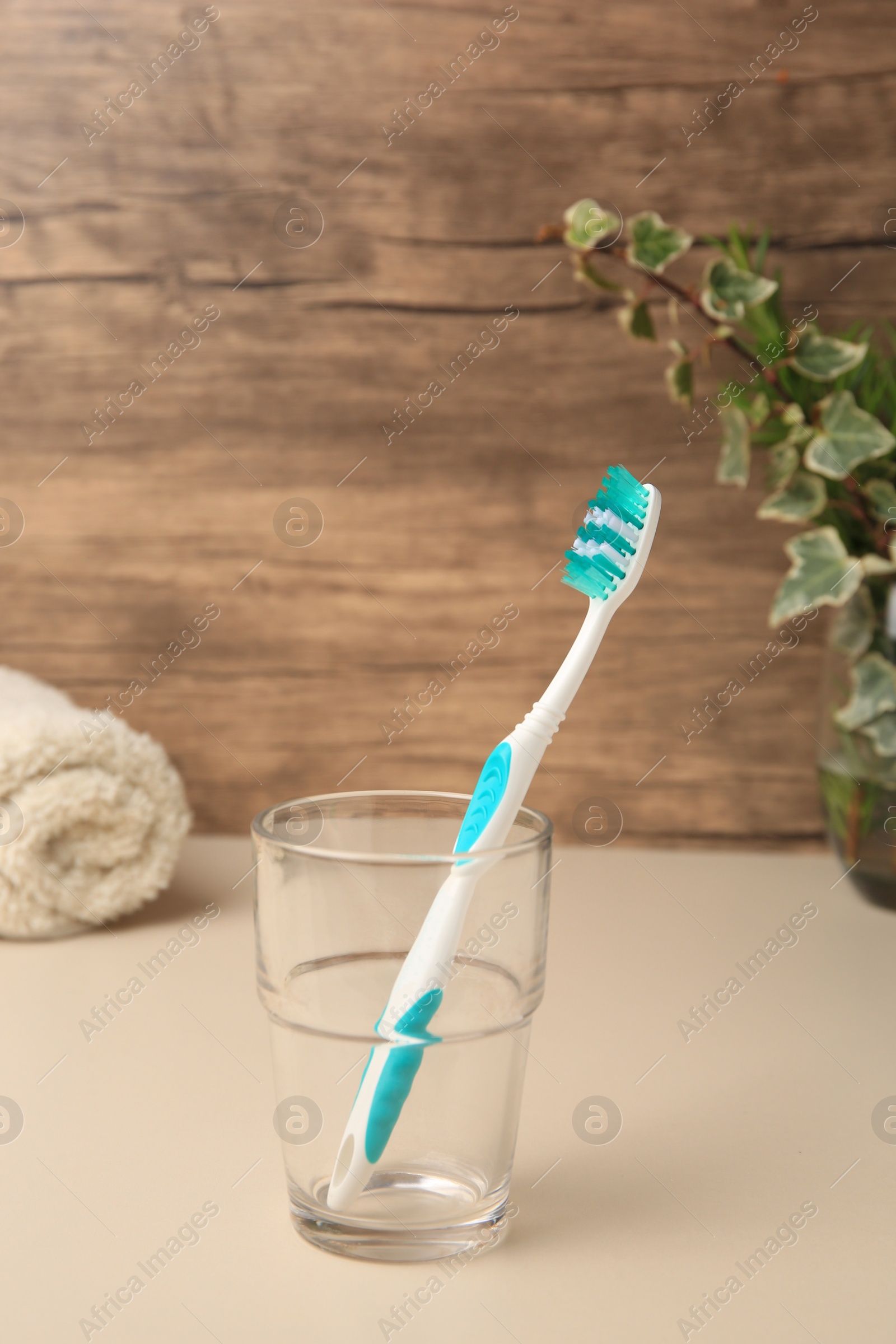 Photo of One toothbrush in glass on beige table