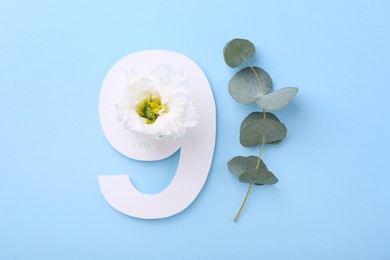 Photo of Paper number 9, beautiful flower and eucalyptus branch on light blue background, top view