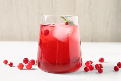 Photo of Tasty cranberry juice in glass and fresh berries on white wooden table, closeup
