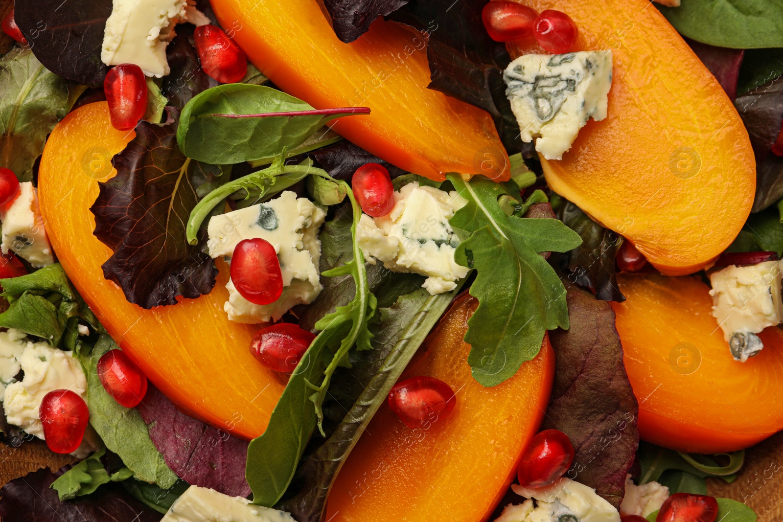 Photo of Delicious persimmon salad with cheese and pomegranate as background, top view
