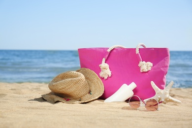 Photo of Stylish beach accessories on sand near sea. Space for text