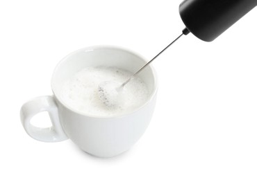 Whisking milk in cup with mini mixer (frother wand) isolated on white, closeup