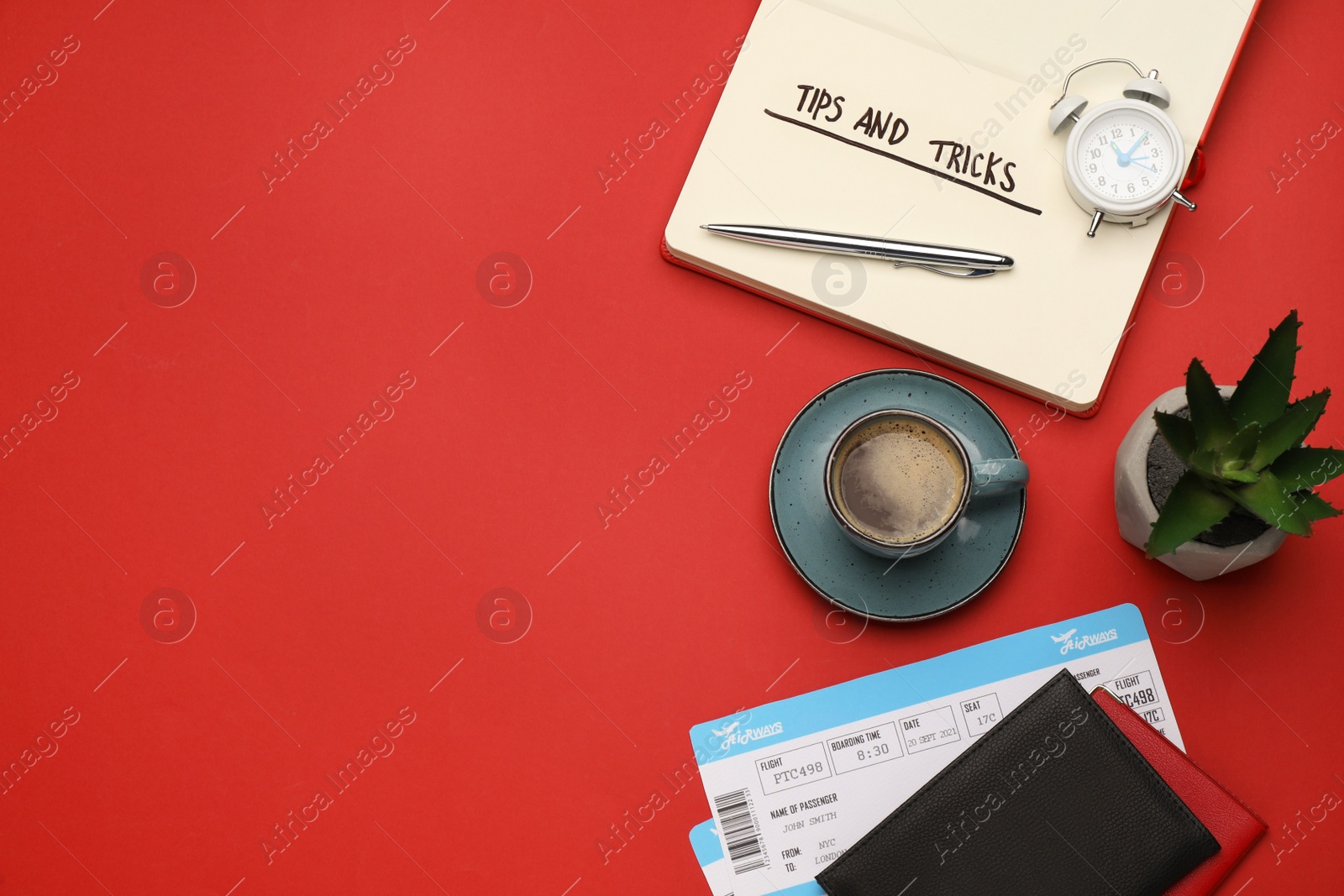 Photo of Flat lay composition with phrase Travel Tips written in notebook, passports, tickets and cup of coffee on red background. Space for text