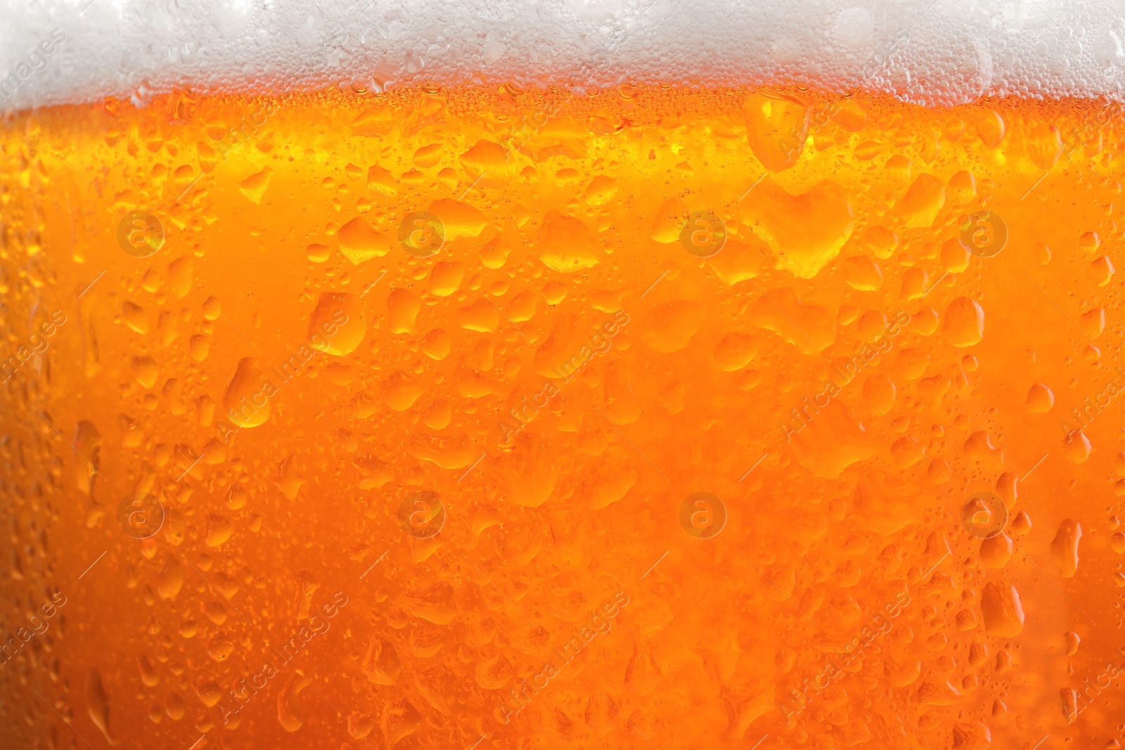 Photo of Glass of tasty cold beer with foam and condensation drops as background, closeup