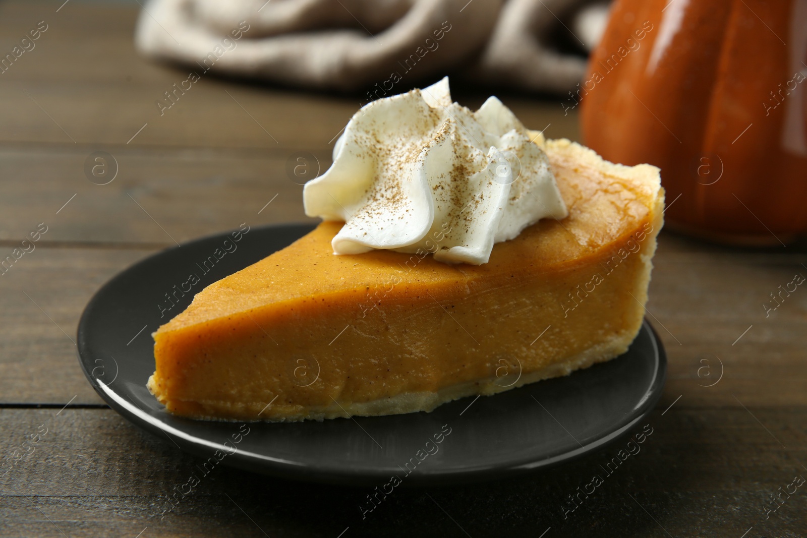 Photo of Piece of delicious pumpkin pie with whipped cream on wooden table, closeup